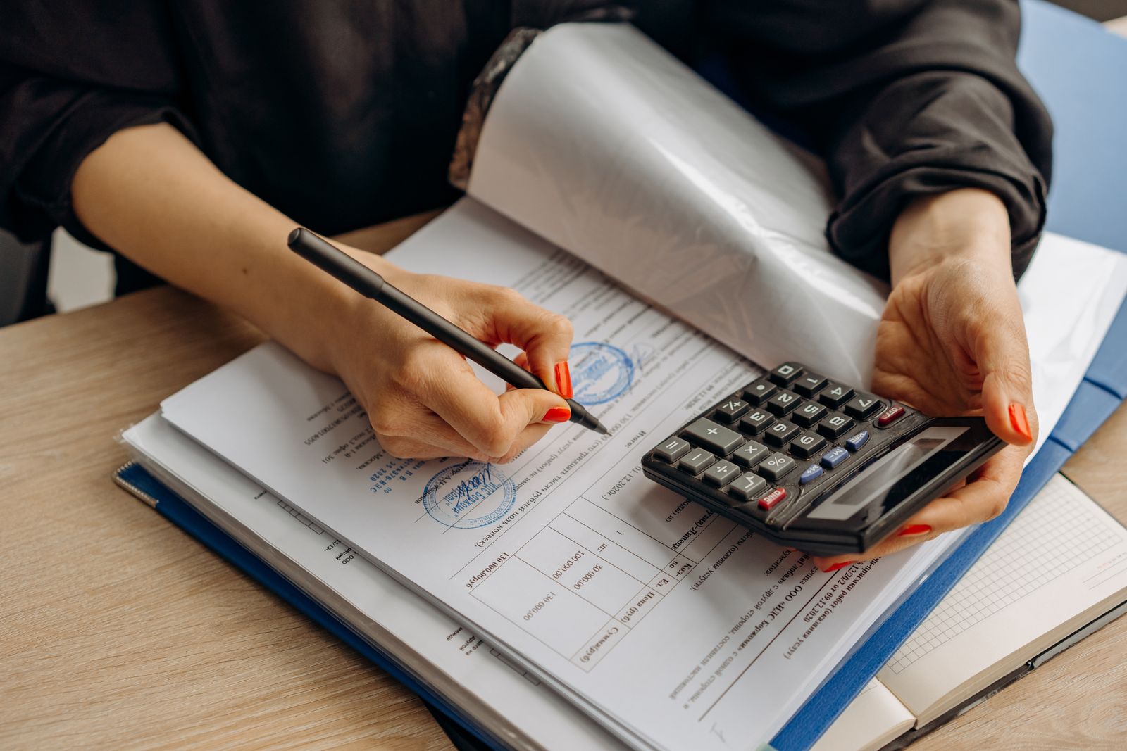 An accountant using a calculator and signing paperwork, showcasing financial analysis.